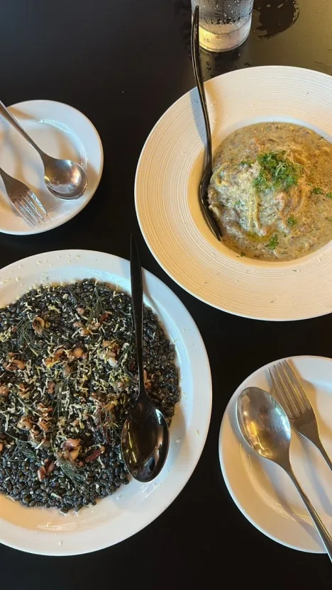 皿に盛られたイカスミリゾットとクリームパスタ